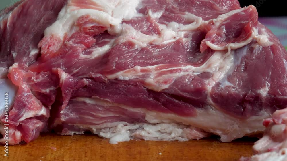 Cook cuts pork in kitchen. Raw meat with fat. Wooden board with onion background in kitchen Cook cuts pork in kitchen. Raw meat with fat. Wooden board with onion background in kitchen