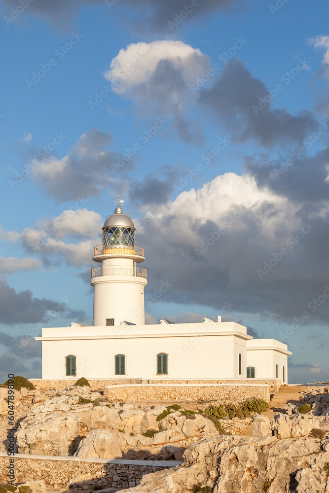 Caballería lighthouse in Menorca island, Spain, at sunset with grey clouds.