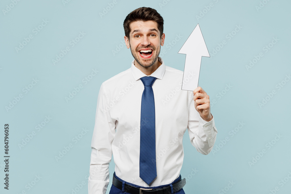 Young happy surprised shocked employee IT business man corporate lawyer wears classic formal shirt tie work in office holding up arrow isolated on plain pastel light blue background studio portrait. Young happy surprised shocked employee IT business man corporate lawyer wears classic formal shirt tie work in office holding up arrow isolated on plain pastel light blue background studio portrait.
