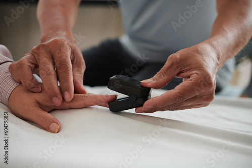 Closeup image of man using odometer to estimate saturation of oxygen in blood of his wife