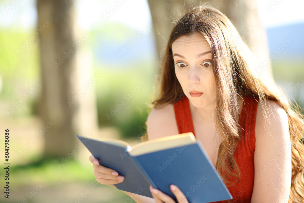 Obraz premium Perplexed reader reading a paper book outdoors