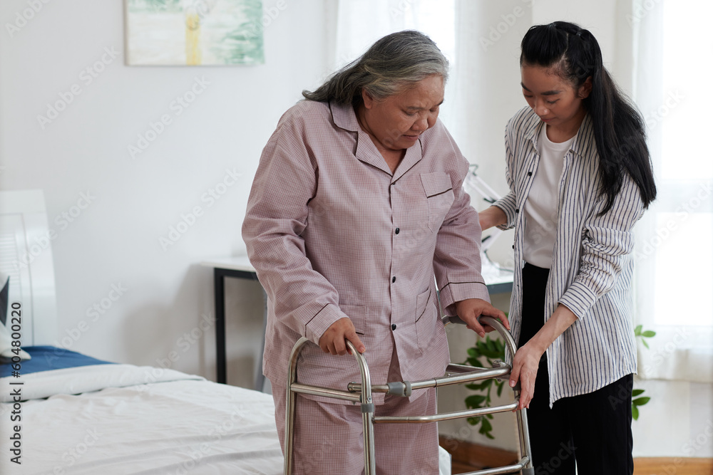 Fototapeta premium Senior woman using walker for the first time under control of her adult daughter