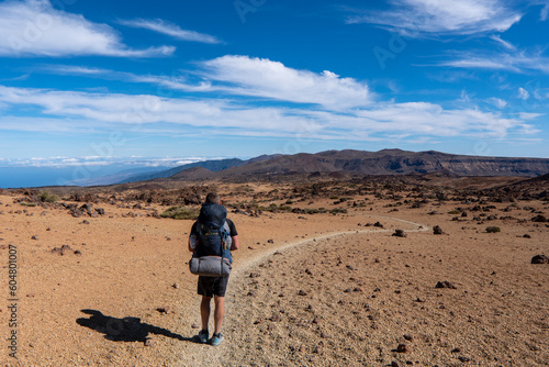 Man on rock with view on La Canada de los Guancheros dry desert plain and volcano Pico del Teide, Mount Teide National Park, Tenerife, Canary Islands, Spain, Europe. Hiking to Riscos de la Fortaleza photo