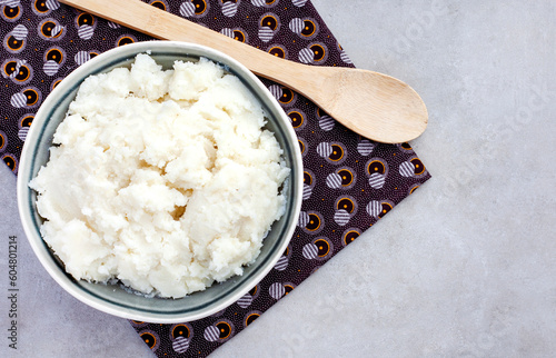 flat lay of Traditional South African pap or maize meal served plain in a bowl with wooden spoon on traditional South African cloth. Shwe shwe. copy space on light grey 