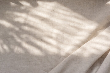 Beige linen fabric texture with folds and natural floral sunlight shadows, aesthetic summer wedding bohemian background