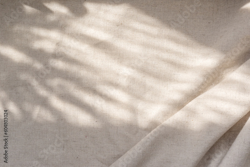 Beige linen fabric texture with folds and natural floral sunlight shadows, aesthetic summer wedding bohemian background