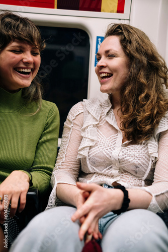 Happy female friends sitting in subway