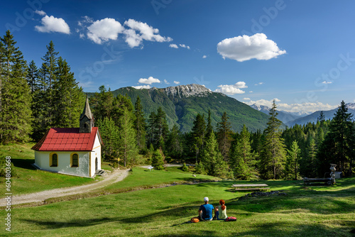 Austria, Tyrol, Hiking pair resting in front of alpine chapel photo