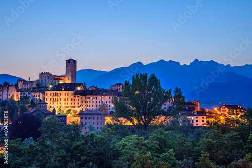 Italy, Veneto, Feltre, Illuminated town in Dolomites at dusk