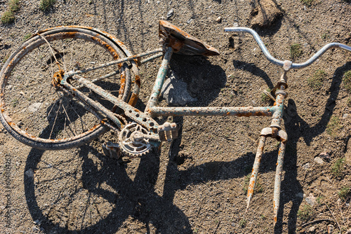 Old rusty bicycle completely incrusted lying on ground, The image captures the essence of decay and abandonment, for clients looking to illustrate themes of neglect, disuse, or urban decay. photo