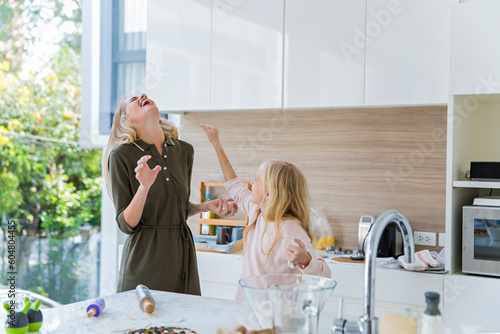 Playful daughter enjoying with mother in kitchen at home photo