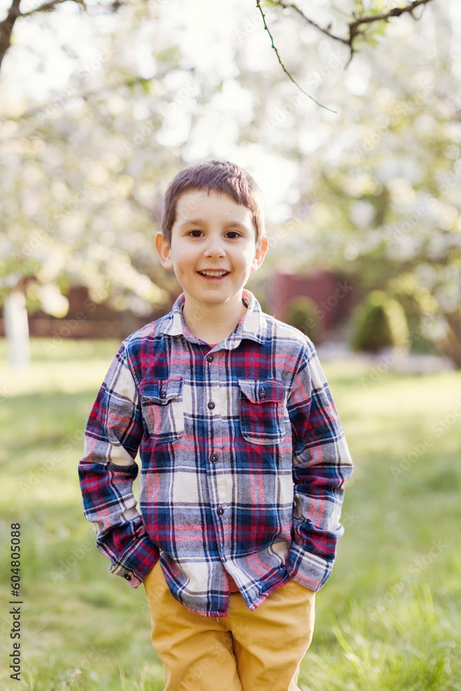 Smiling boy with hands in pockets standing at back yard Smiling boy with hands in pockets standing at back yard