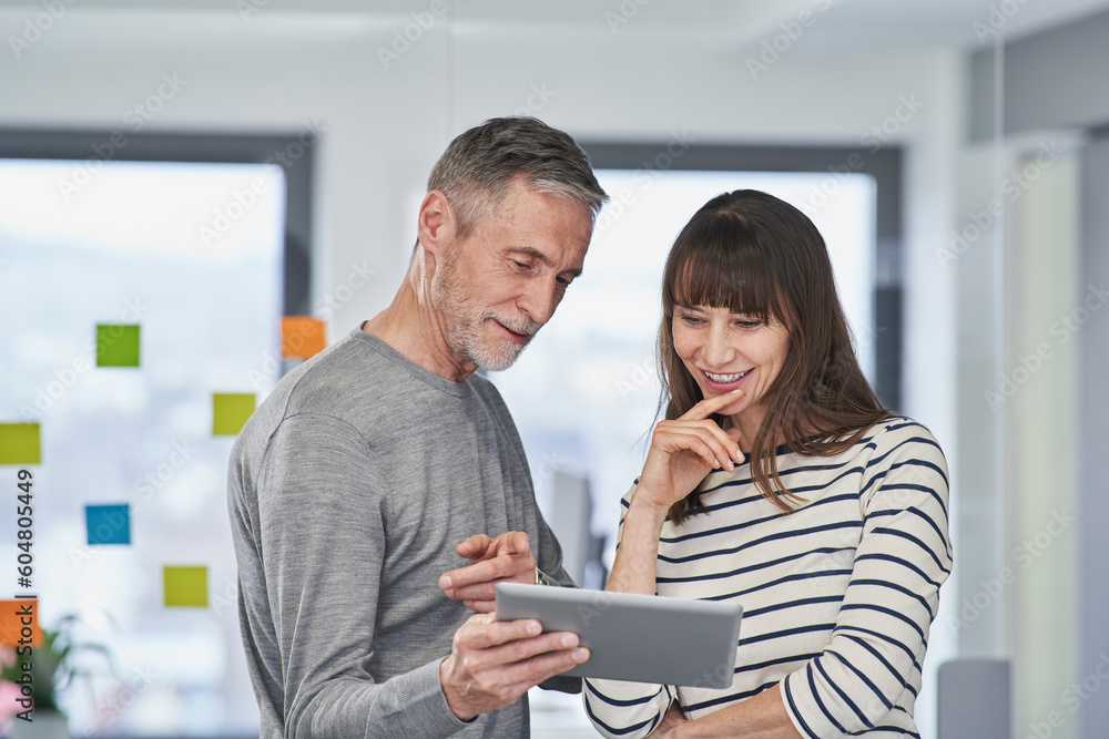 Businessman pointing over tablet PC to colleague in office Businessman pointing over tablet PC to colleague in office