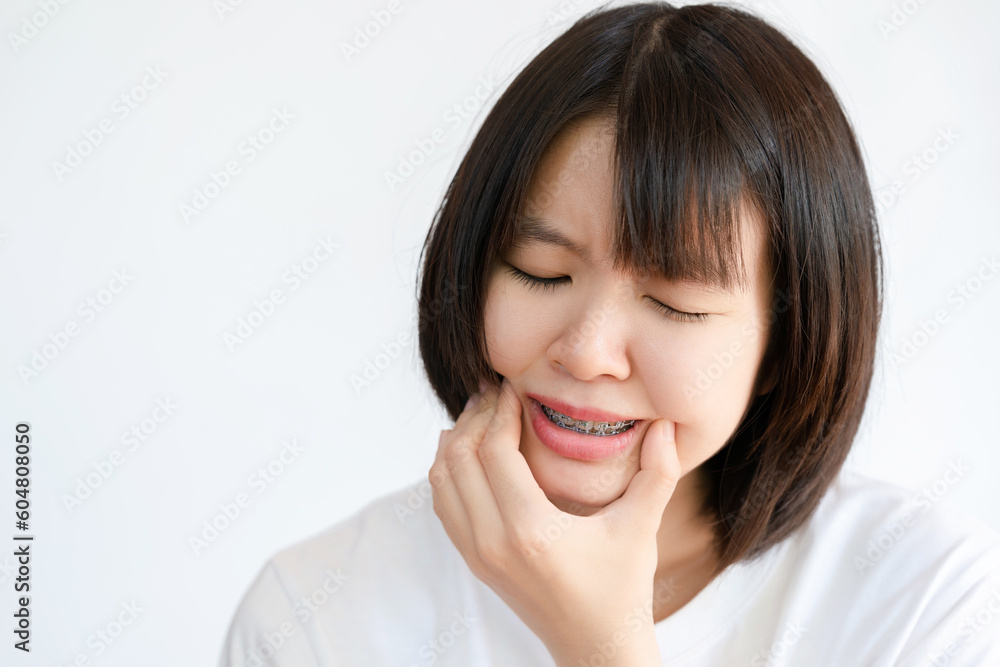 A woman touches her cheek due to a toothache after wearing braces. A woman touches her cheek due to a toothache after wearing braces.