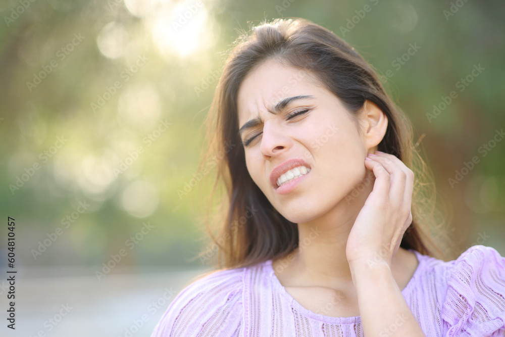 Stressed woman scratching neck in a park Stressed woman scratching neck in a park
