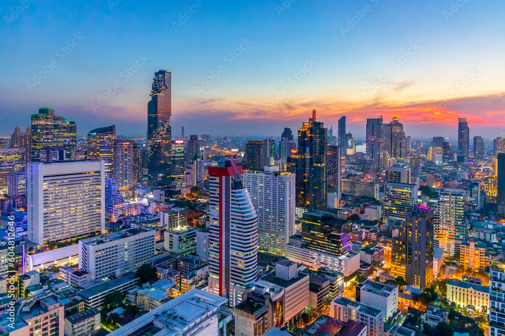 Obraz premium Cityscape panorama of city in twilight sunset.Beautiful blue sky with space.Business area skyscraper building.Trade center in town.Light technology form city.Yellow and orange light.Aerial view.