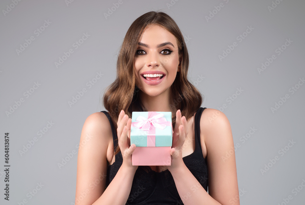 Sexy woman hold gift, isolated on gray studio background. Holidays celebration concept. Celebrating birthday, receive gift present. Surprised girl with gift. Portrait of attractive woman with gift. Sexy woman hold gift, isolated on gray studio background. Holidays celebration concept. Celebrating birthday, receive gift present. Surprised girl with gift. Portrait of attractive woman with gift.
