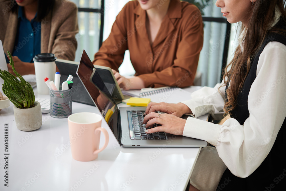Cropped image of business women working on laptops at office table Cropped image of business women working on laptops at office table