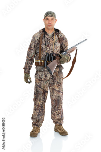 Duck hunter with a rifle on his hand and binoculars on the neck. Portrait of fifty-year-old man in hunting uniform isolated on white background. Mature hunter with a shotgun posing in studio.