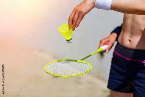 Badminton racket and yellow shuttlecock in hand of young woman close-up outdoors, copy space, sport and healthy lifestyle concept © Yelena
