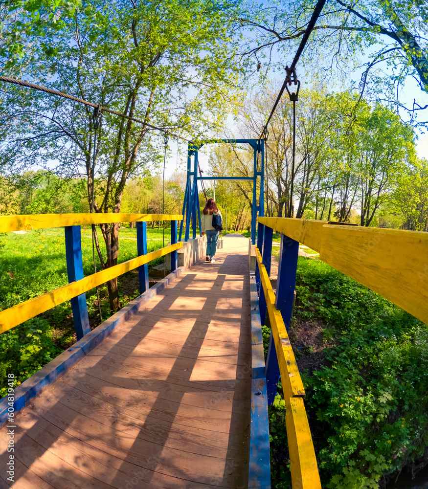 Tourist crossing Seret river by the wooden bridge. Colorful spring view of Topilche park, Ternopil, Ukraine, Europe. Traveling concept background. Tourist crossing Seret river by the wooden bridge. Colorful spring view of Topilche park, Ternopil, Ukraine, Europe. Traveling concept background.