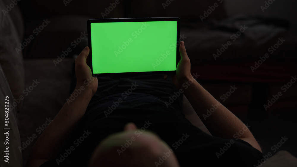 Naklejka premium Man at home lying on a couch with tablet pc with green screen