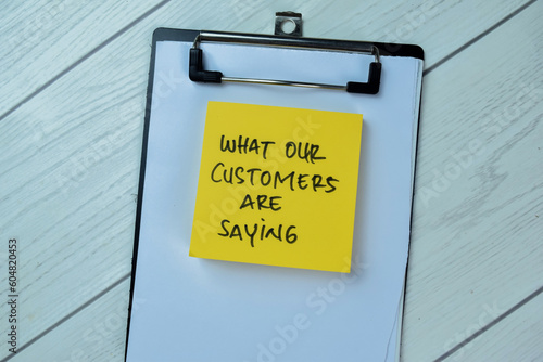 Concept of What Our Customers Are Saying write on sticky notes isolated on Wooden Table.
