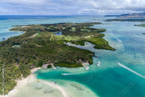 Beautiful island beach with palm trees and blue sky leading out to the open ocean. Ile Aux Cerfs, Mauritius. Aerial view of sandy beach and golf course. Aerial drone view of the tropical ocean