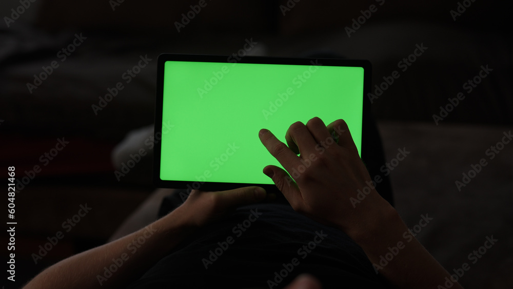 Naklejka premium Man at home lying on a couch with tablet pc with green screen