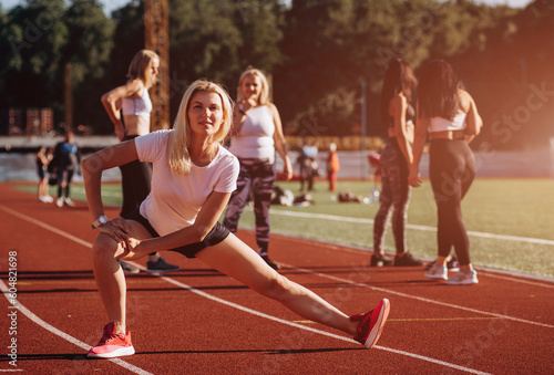 Sport in open air and health care concept. attractive fitness woman warm-up before run on the stadium track on sunny summer day.