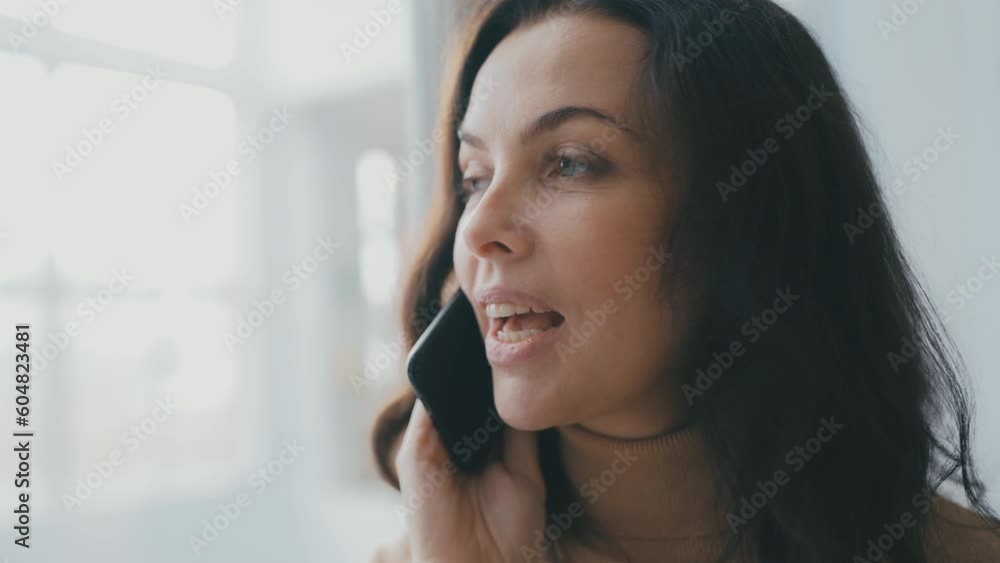 Closeup of happy woman talking on mobile phone while looking out the window Closeup of happy woman talking on mobile phone while looking out the window