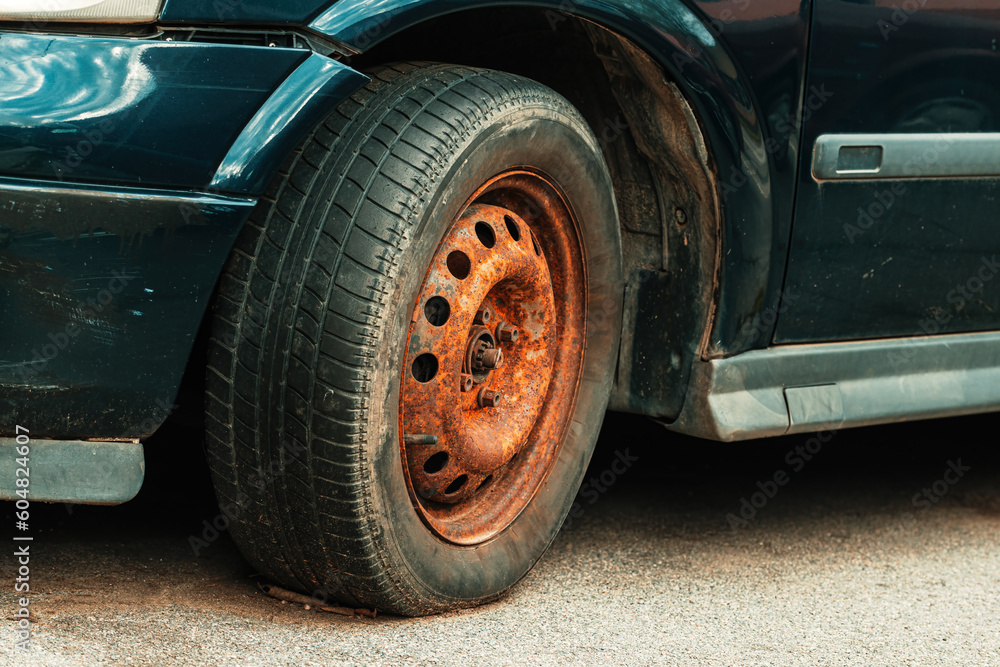 Old rusty car wheel rim and worn tire