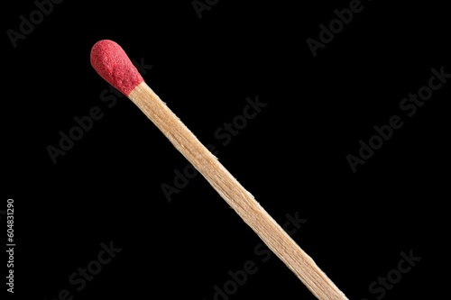 Matchstick with its red match and its wooden stick in extreme close-up on a black background