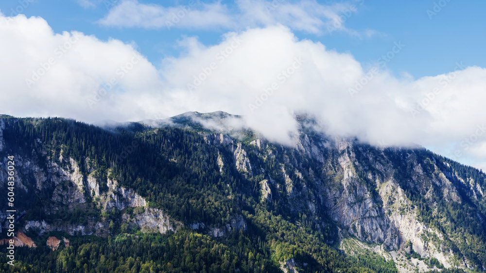 Panoramic mountain landscape. Mountain stone peaks in the clouds on a sunny day.