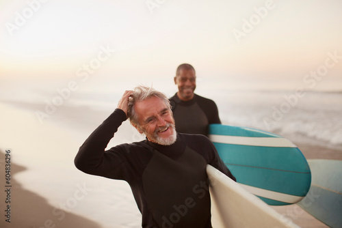 Φωτογραφία Older surfers carrying boards on beach