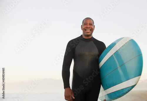 Canvas Print Older surfer carrying board on beach