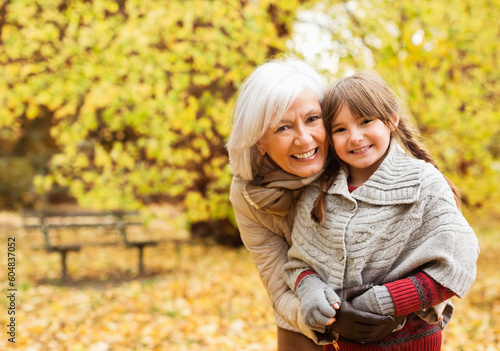 Older woman and granddaughter smiling in park