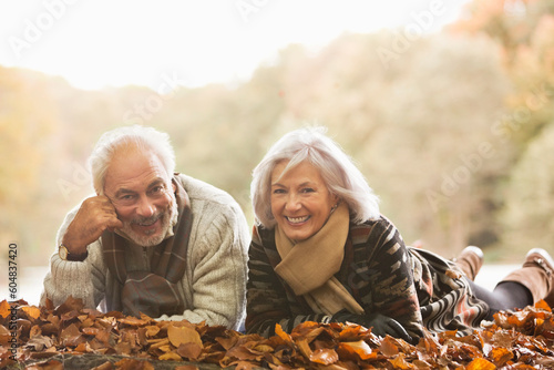 Older couple laying in autumn leaves