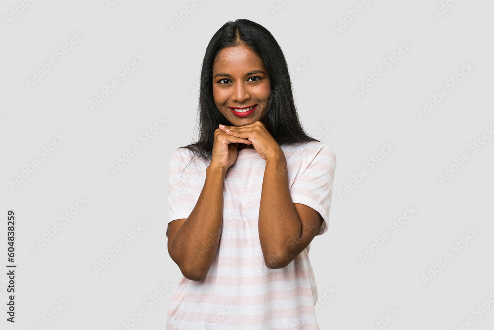 Young Indian woman cut out isolated on white background keeps hands under chin, is looking happily aside. Young Indian woman cut out isolated on white background keeps hands under chin, is looking happily aside.