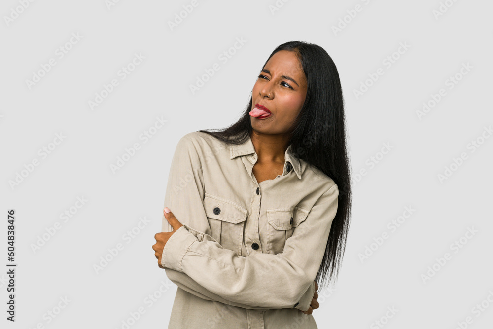Young Indian woman cut out isolated on white background funny and friendly sticking out tongue. Young Indian woman cut out isolated on white background funny and friendly sticking out tongue.