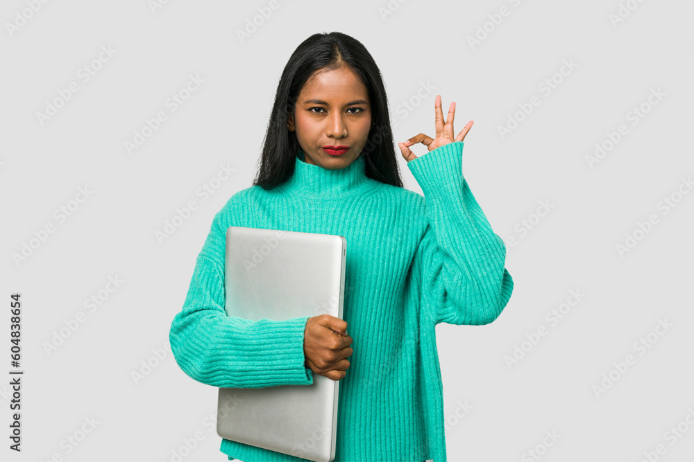 Young indian woman holding a laptop isolated on white background Young indian woman holding a laptop isolated on white background