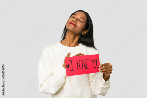 Young Indian woman holding an I love you placard isolated on white background