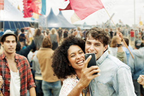 Fotografiet Couple taking self-portrait with camera phone at music festival