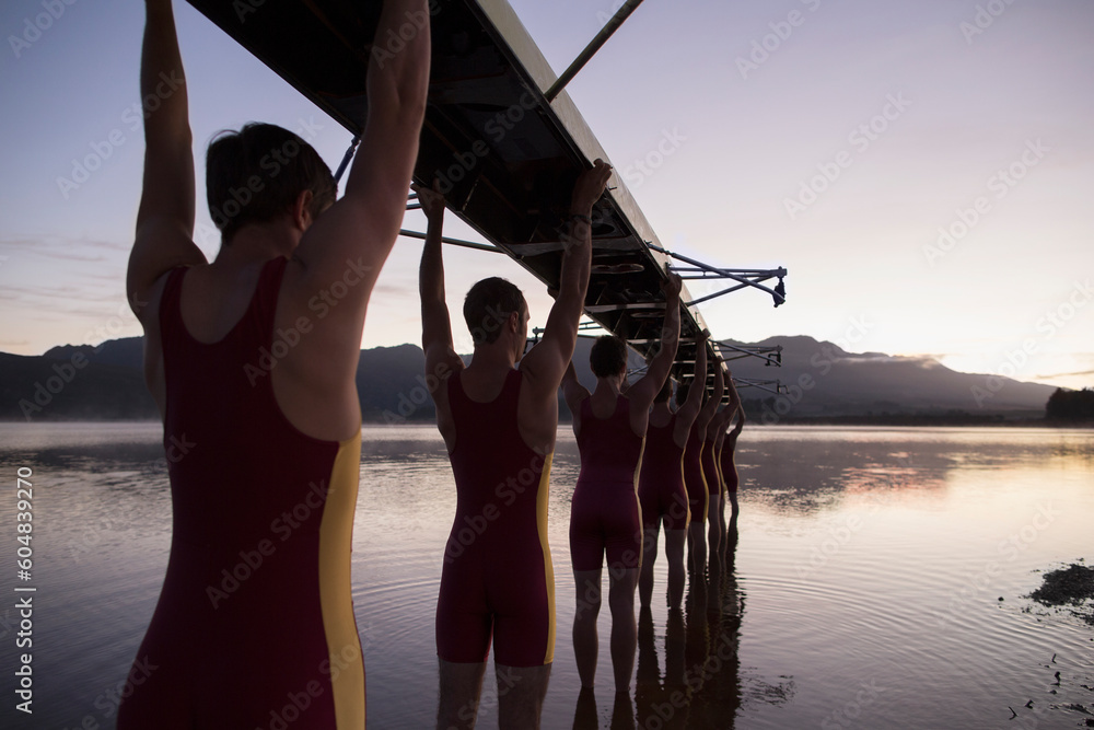 Rowing team carrying boat overhead into lake - obrazy, fototapety, plakaty 