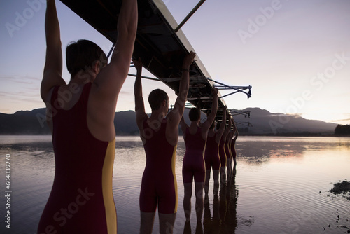 Fotografia Rowing team carrying boat overhead into lake
