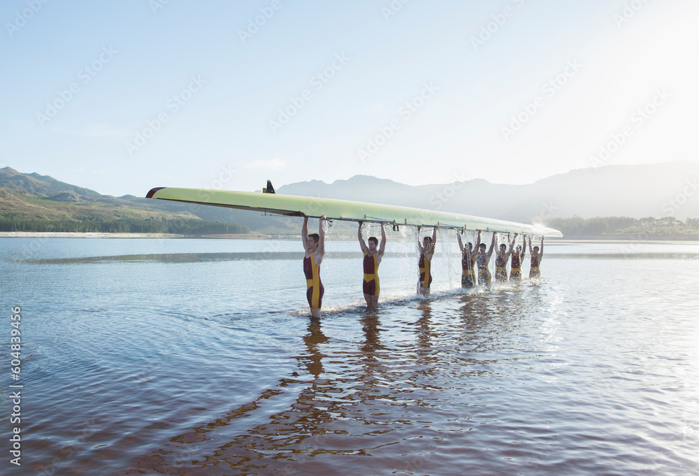 Rowing team holding scull overhead in lake - obrazy, fototapety, plakaty 