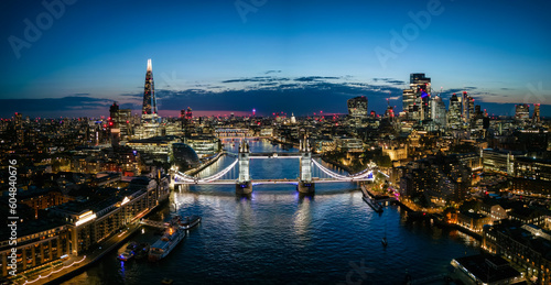 Panoramic aerial view of the famous Tower Bridge and river Thames with the illuminated City skyscrapers during night time, England