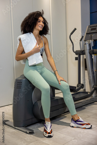 Young woman wiping sweat after the workout in gym