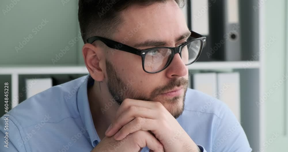 Businessman of Caucasian nationality is sitting behind a desk in his office, looking out the window. His facial expression shows that he is deep in thought and contemplating important matters. Businessman of Caucasian nationality is sitting behind a desk in his office, looking out the window. His facial expression shows that he is deep in thought and contemplating important matters.