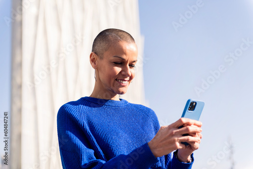 Принти на полотні confident woman in blue sweater using mobile phone at city, concept or modern li